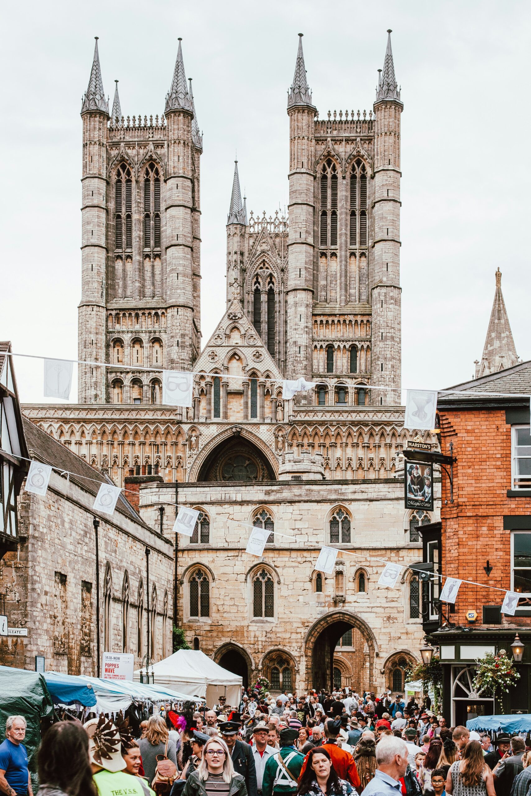 View of the Louth Cathedral showcasing its stunning Gothic architecture, with intricate stonework, tall spire, and arched windows against a clear sky.